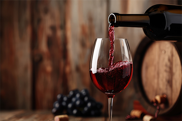 a bottle of wine being poured into a wine glass next to a wine barrel